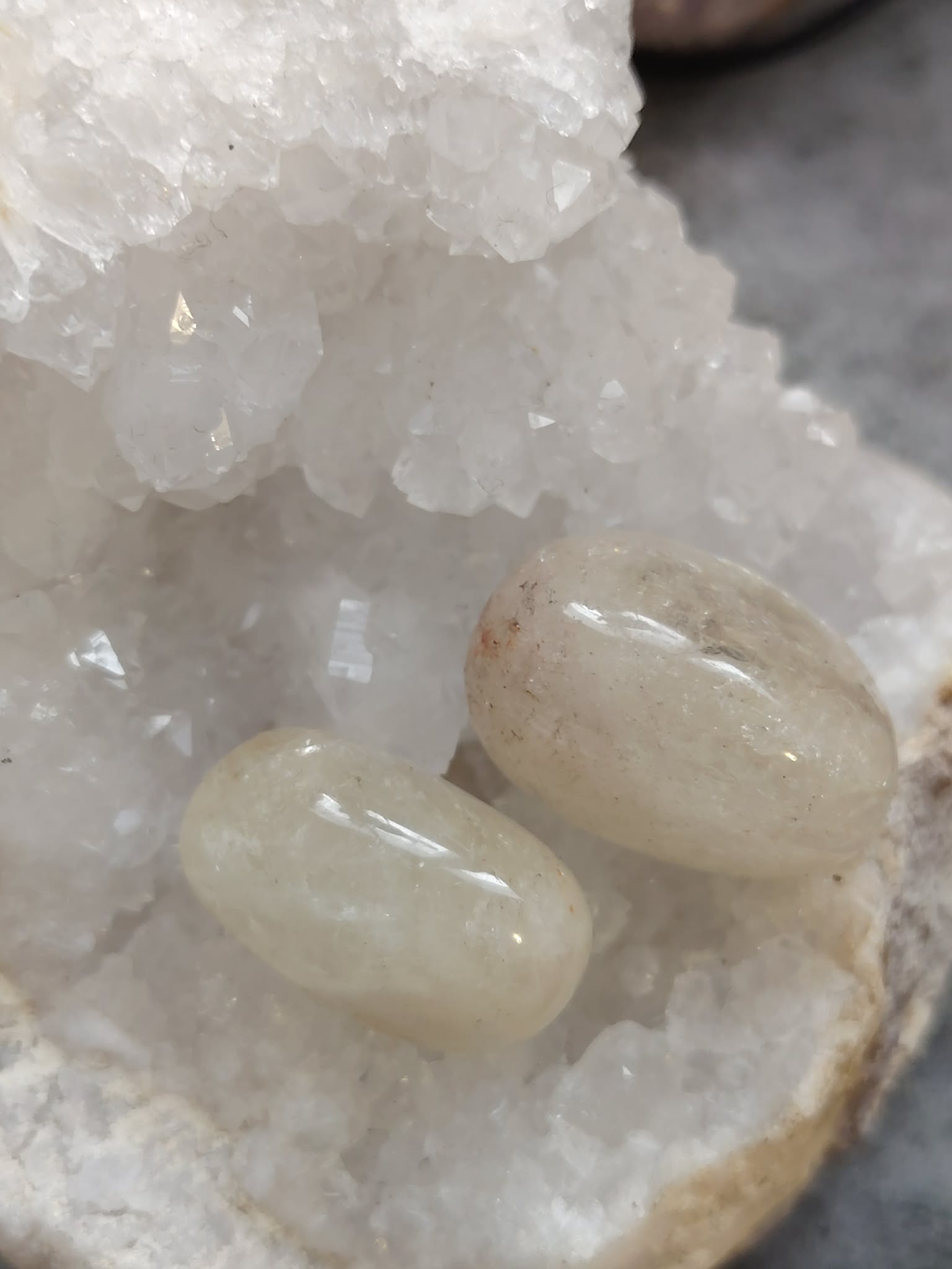 Deux pierres roulées citrine posées sur support naturel avec amas de quartz en arrière-plan, ambiance minérale, lumière douce, énergie solaire, joie, confiance, concentration, motivation, abondance, photo produit Magic Gaïa.