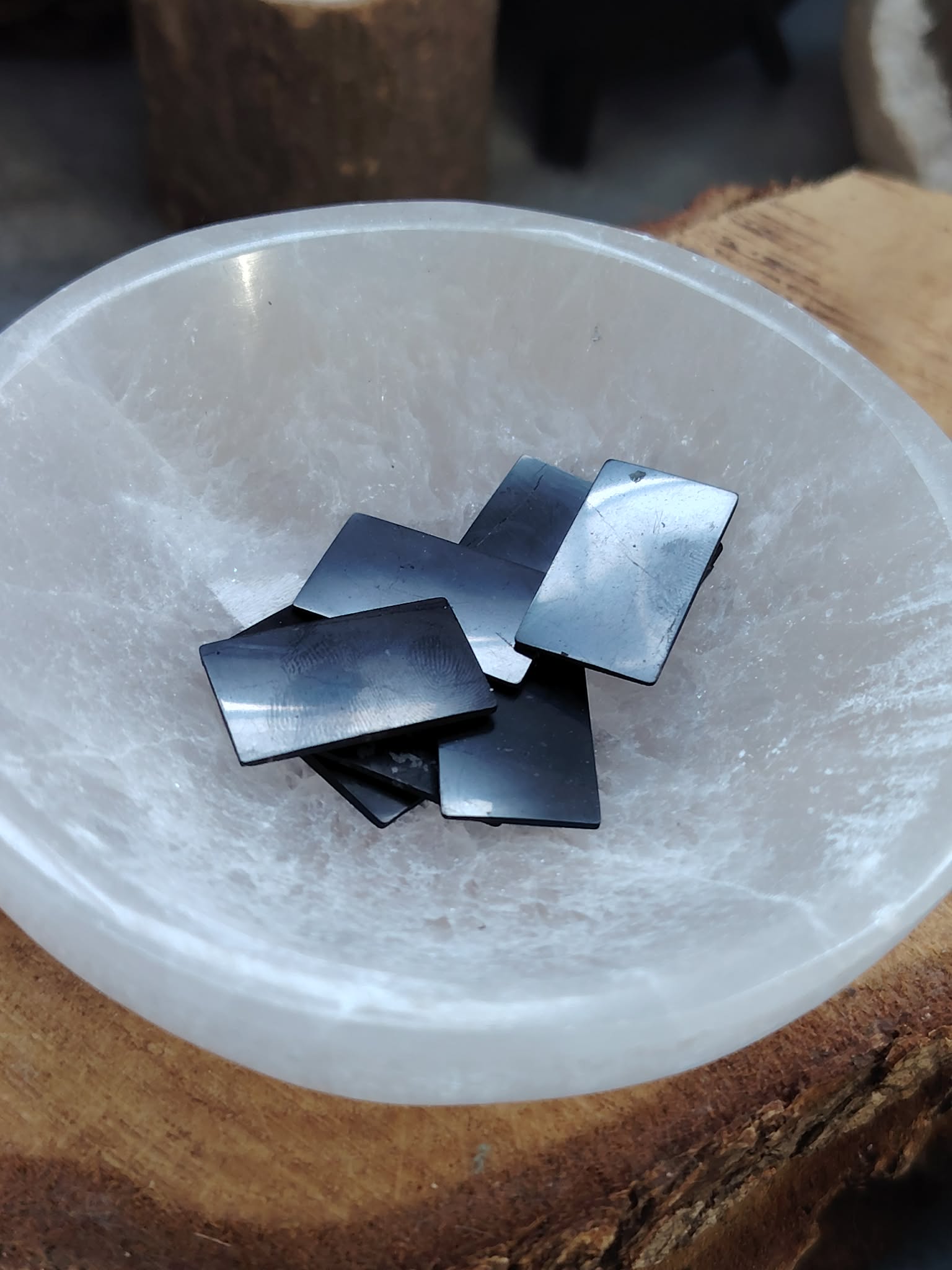 Plaques de shungite pour téléphone (stickers anti-ondes) posées dans un bol blanc de purification, photo produit Magic Gaïa, vertus variées : ancrage, protection, apaisement énergétique.