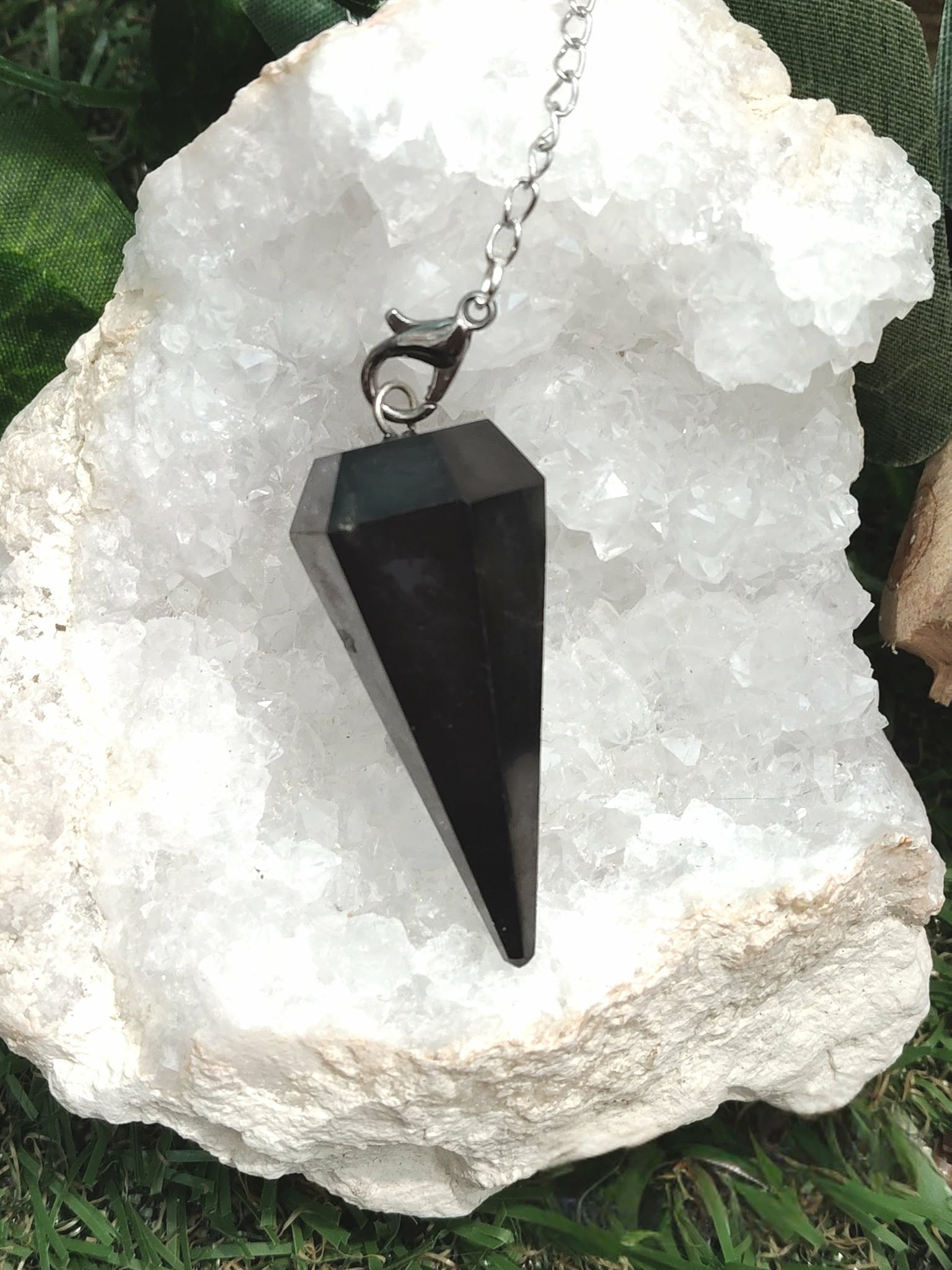 Pendule facetté en shungite noire personnalisable, posé sur cristal de quartz, ambiance naturelle, purification, centrage, stabilité, intuition • Magic Gaïa