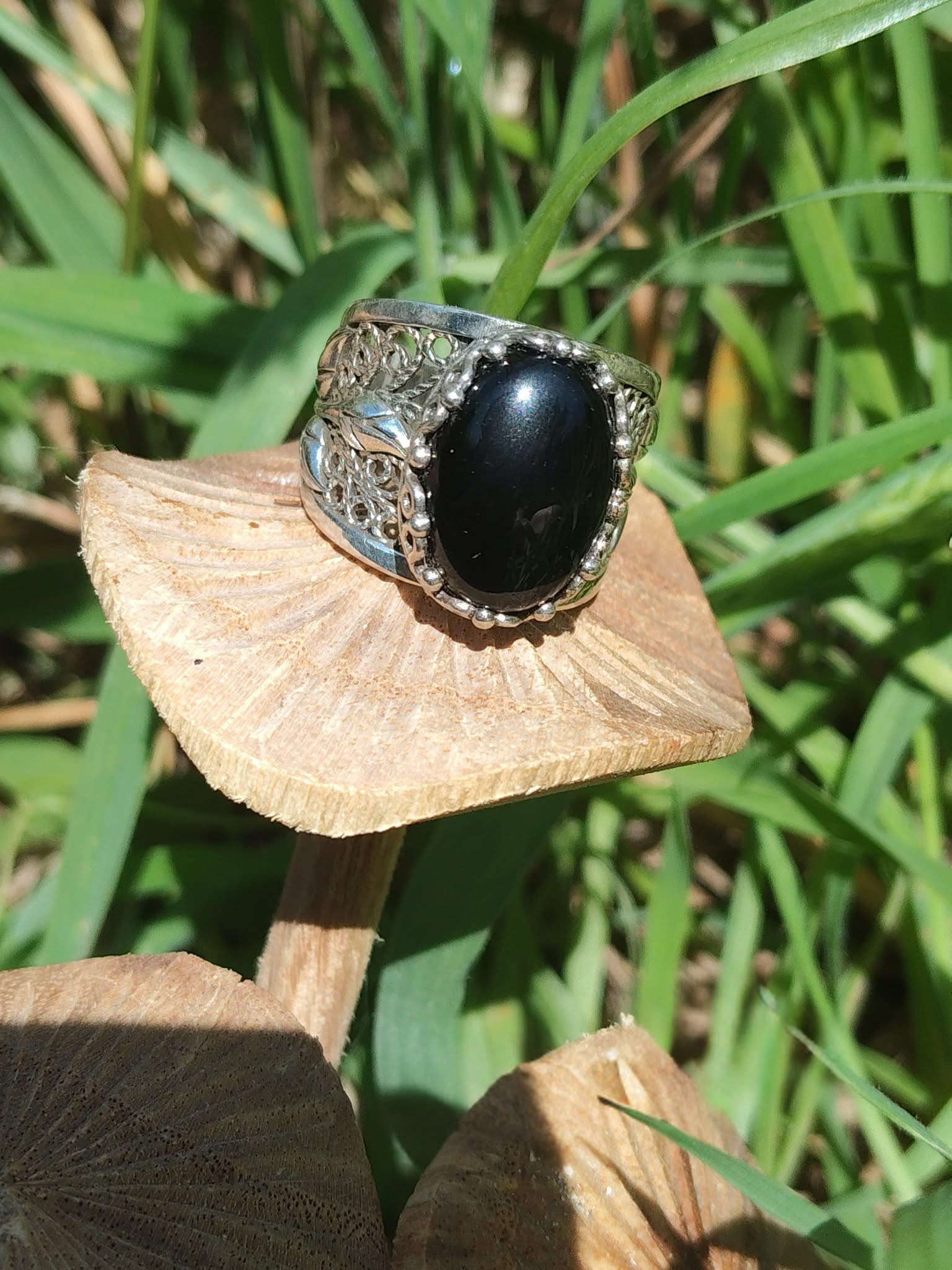 Bague onyx noir argent 925 anneau filigrané photo nature sur feuille beige fond herbes vertes intentions associées calme maîtrise de soi discernement
