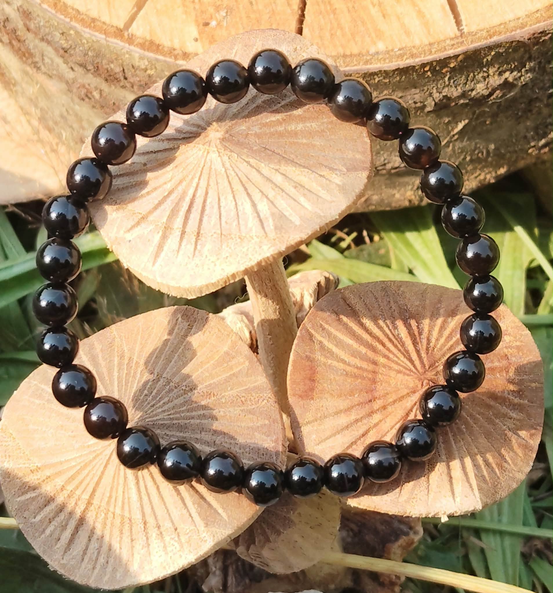Bracelet Onyx noir en perles lisses rondes, vue du dessus en décor naturel, recentrage, maîtrise intérieure et solidité émotionnelle.