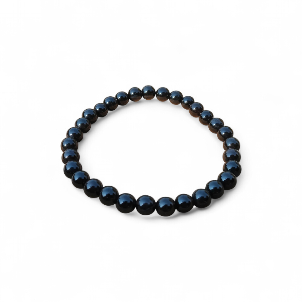 Bracelet Onyx noir en perles rondes sur élastique, présenté sur fond blanc, force calme, discernement et tenue intérieure.