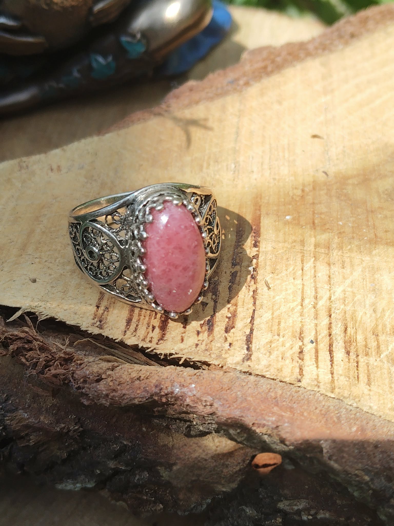 Bague rhodonite ovale rose filigrane argent 925 mise en scène sur bois et écorce décor nature intentions protection douce apaisement harmonisation