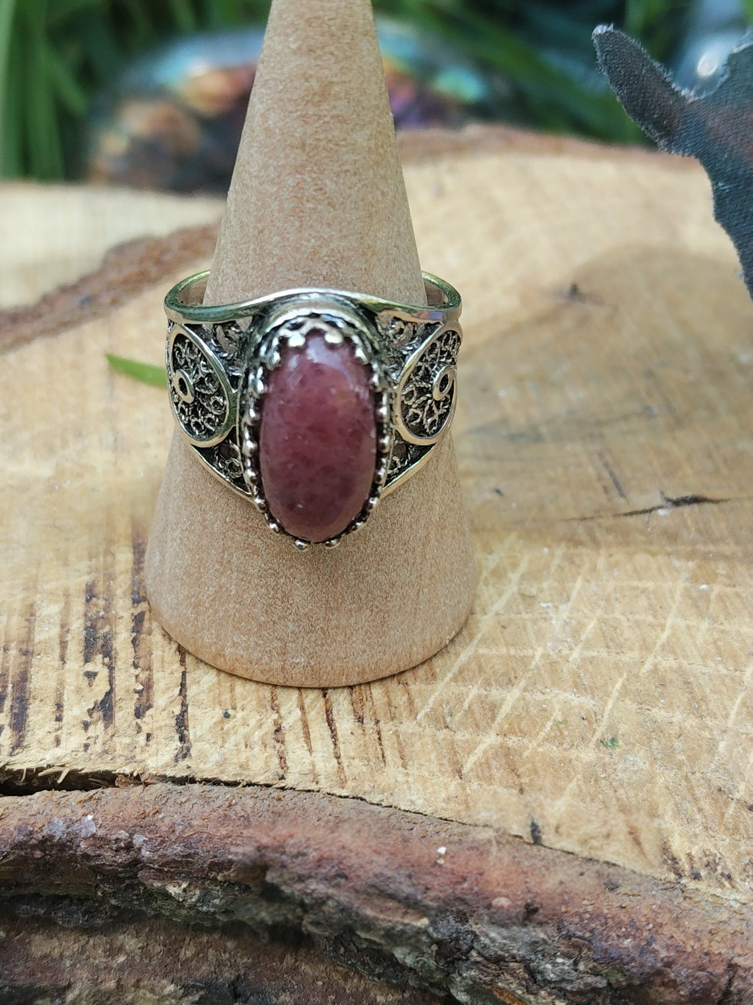 Bague argent 925 filigrane pierre rhodonite rose ovale présentée sur porte-bague en bois fond bois et lumière douce intentions harmonie du cœur calme intérieur