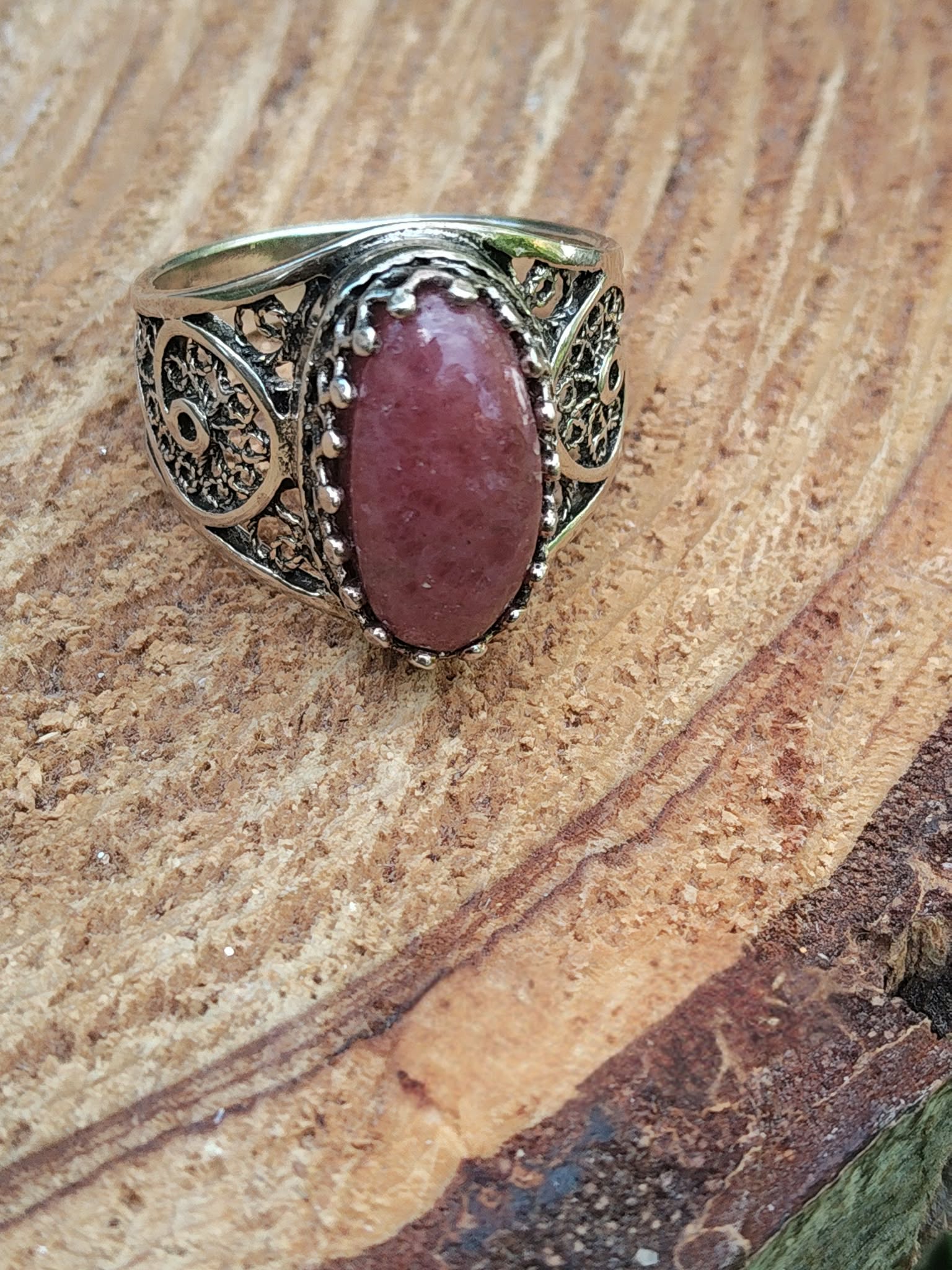 Bague rhodonite ovale rose monture ajourée filigranée argent 925 sur décor bois et mousse intentions apaisement recentrage