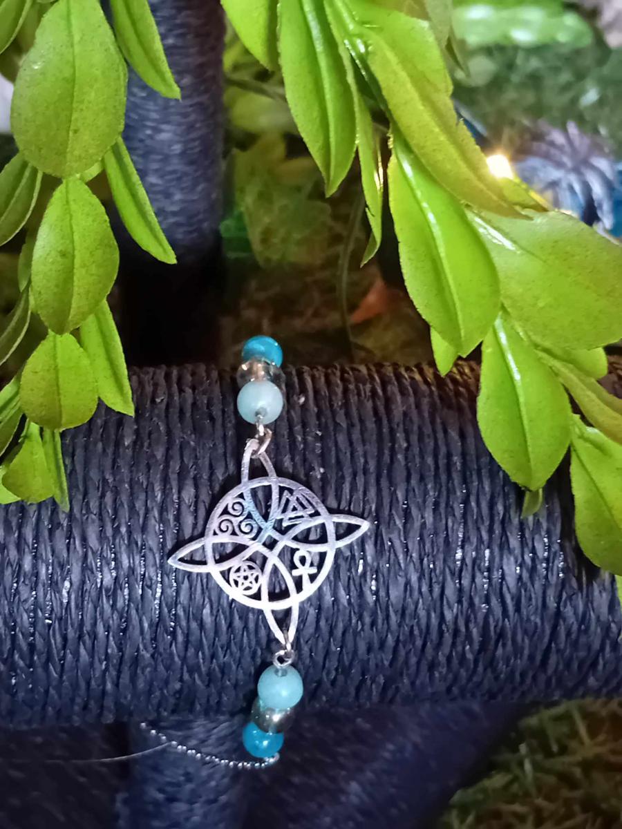 Bracelet symbole antique argenté ajouré, amazonite, apatite, aqua aura décor végétal vert sur fond sombre texturé, lumière naturelle, aide à l’apaisement, à la communication, à l’équilibre émotionnel et au recentrage.