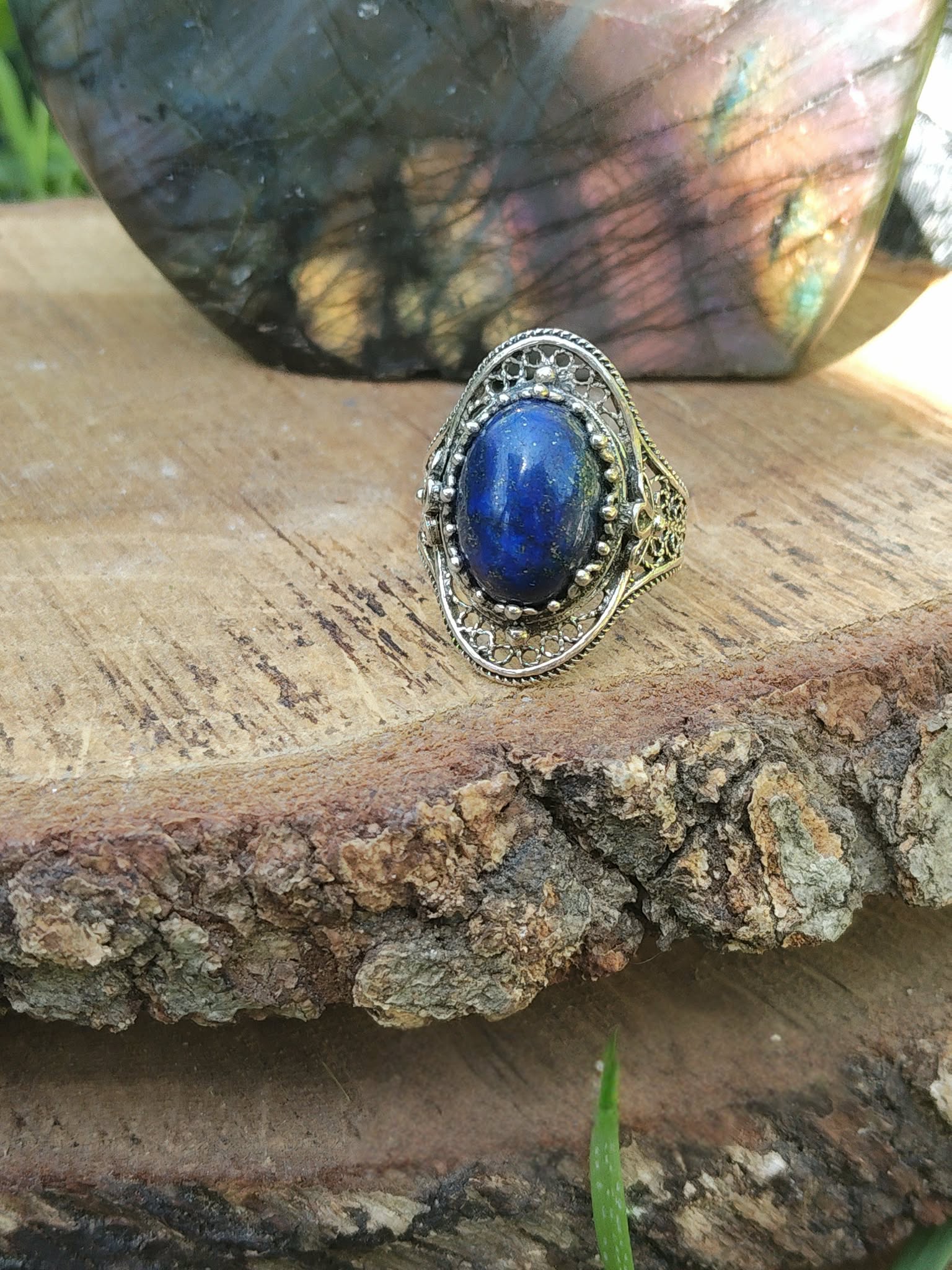 Bague argent 925 style filigrane, lapis lazuli bleu vif, présentée sur bois, décor végétal, pour sérénité et communication.