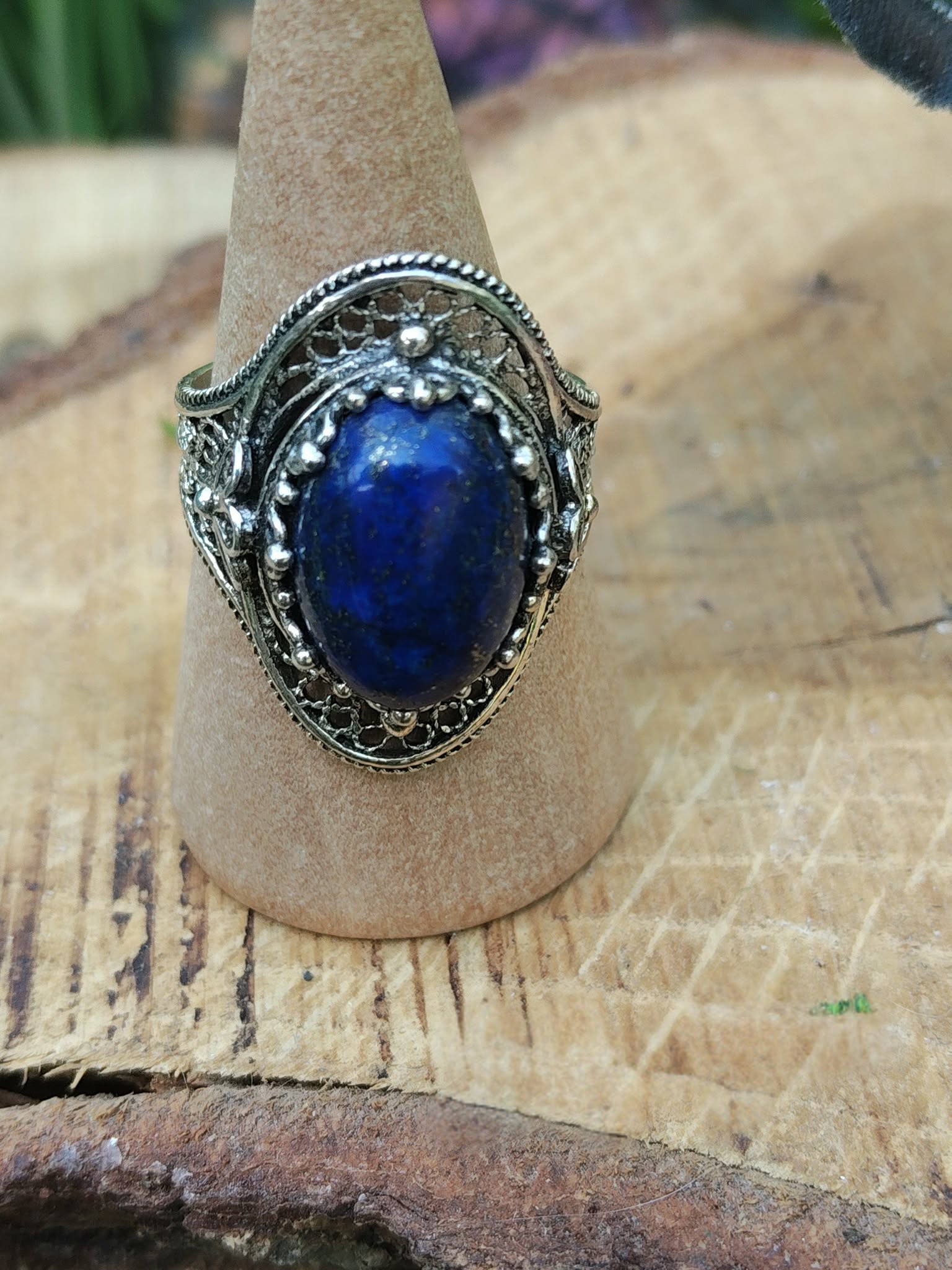 Bague filigrane en argent 925, lapis lazuli bleu intense au centre, présentoir en bois, arrière-plan doux, pour favoriser confiance et expression.