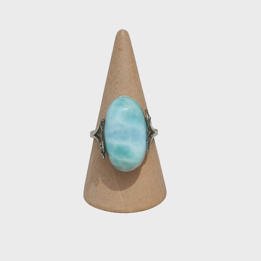 Bague réglable en argent avec larimar bleu ciel, présentée sur cône en bois sur fond clair, idéale pour apaiser, favoriser la communication et la sérénité