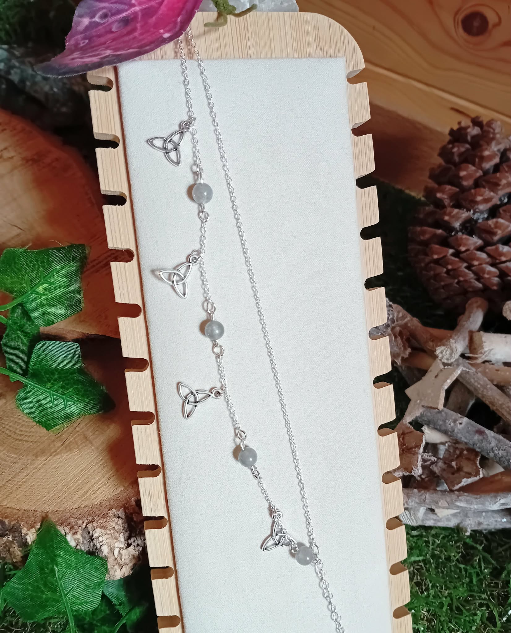 Chaîne de cheville en acier inoxydable avec perles de labradorite et breloques triquetra, présentée sur carton blanc dans une boîte en bois, pour protection douce, ancrage et assurance.