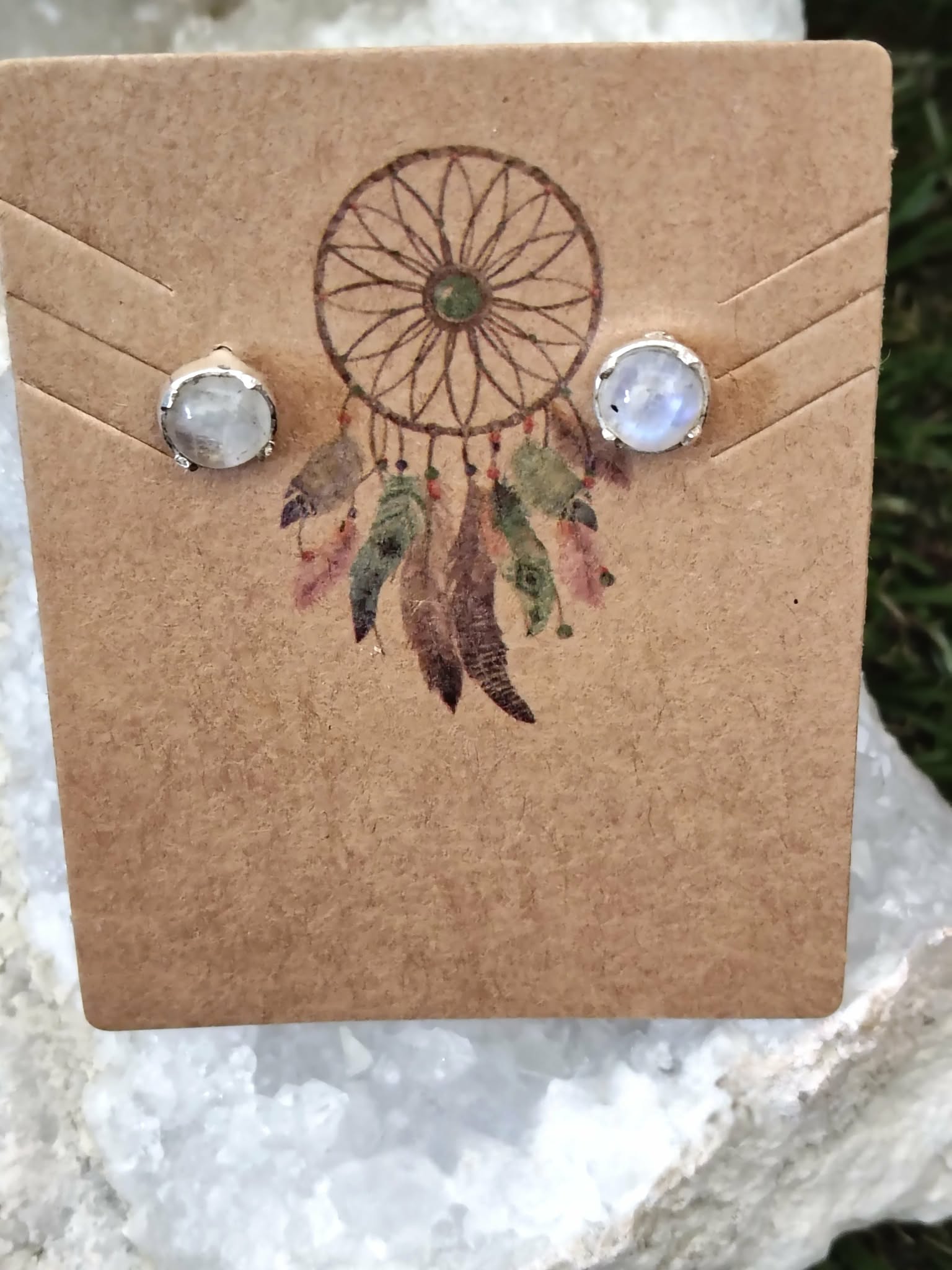 Boucles d’oreilles puces en argent 925 avec péristérite, posées sur carte kraft motif attrape-rêves sur pierre claire, pour apaiser et écouter son intuition.