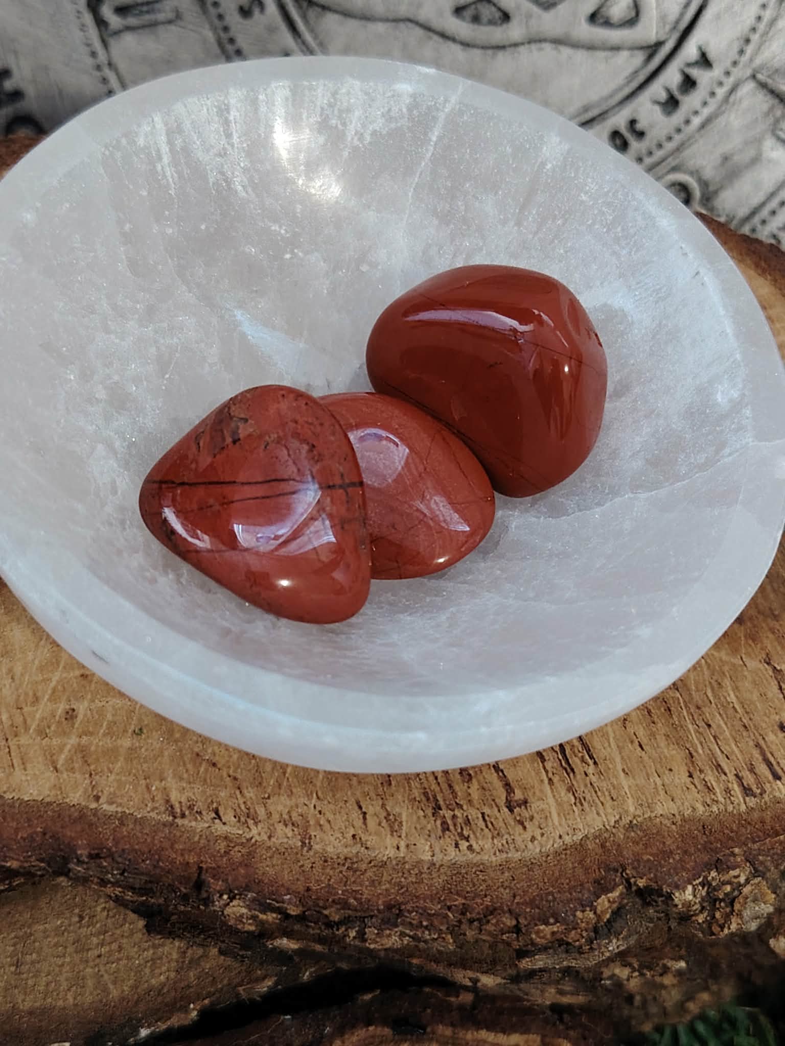 Bol en sélénite blanche avec pierres roulées de jaspe rouge, posé sur rondin de bois, fond motif celtique, pour ancrage, courage et vitalité au quotidien