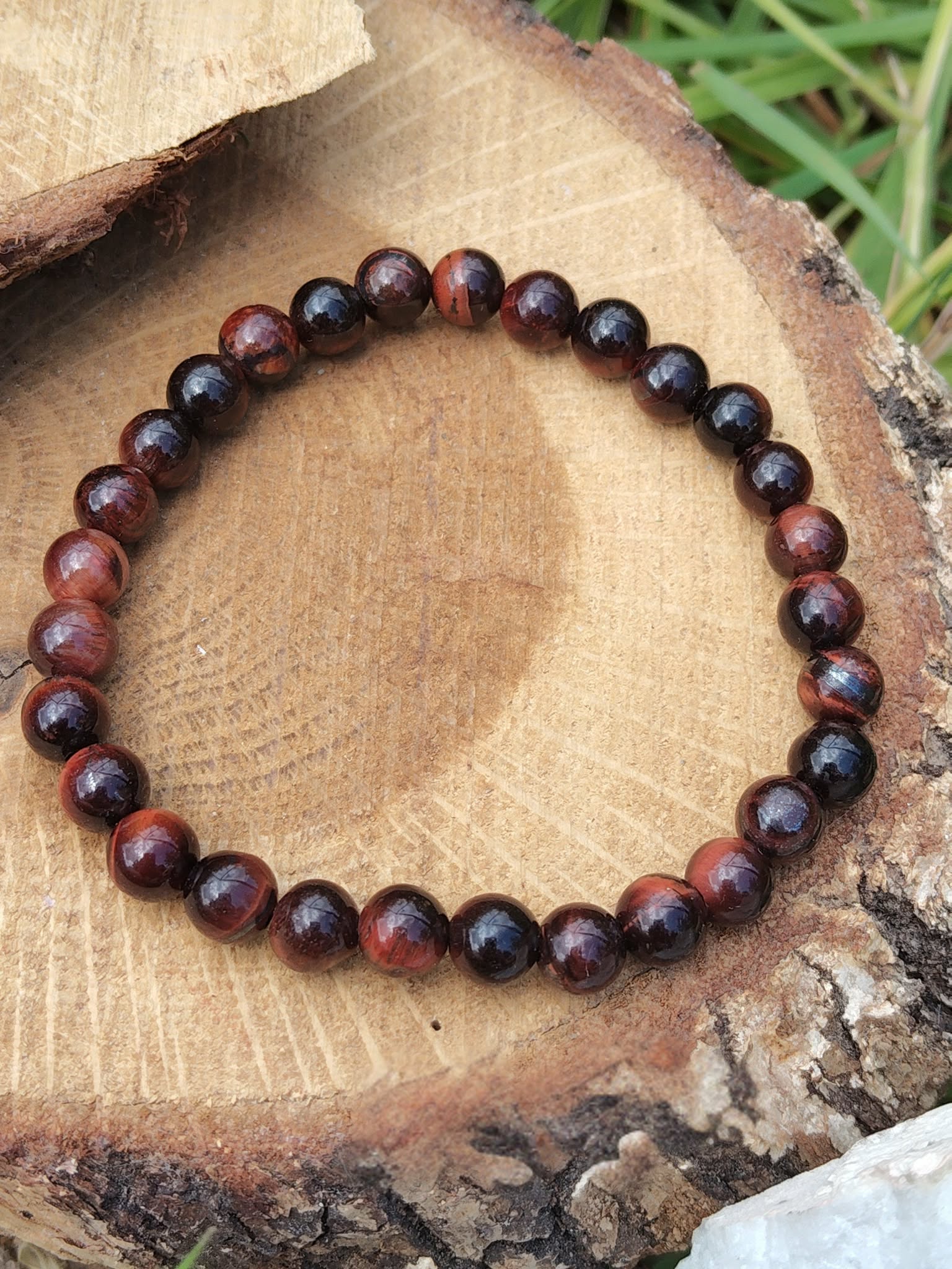 Bracelet œil de taureau 6 mm sur tranche de bois clair avec feuillage, détermination stable et protection symbolique au quotidien