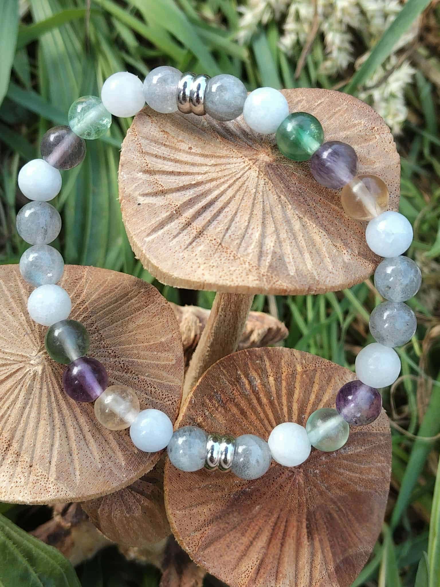 Création bracelet Énergie lunaire posée sur champignons et herbes, perles bleu-gris, blanches, vertes et violettes, bijou apaisant