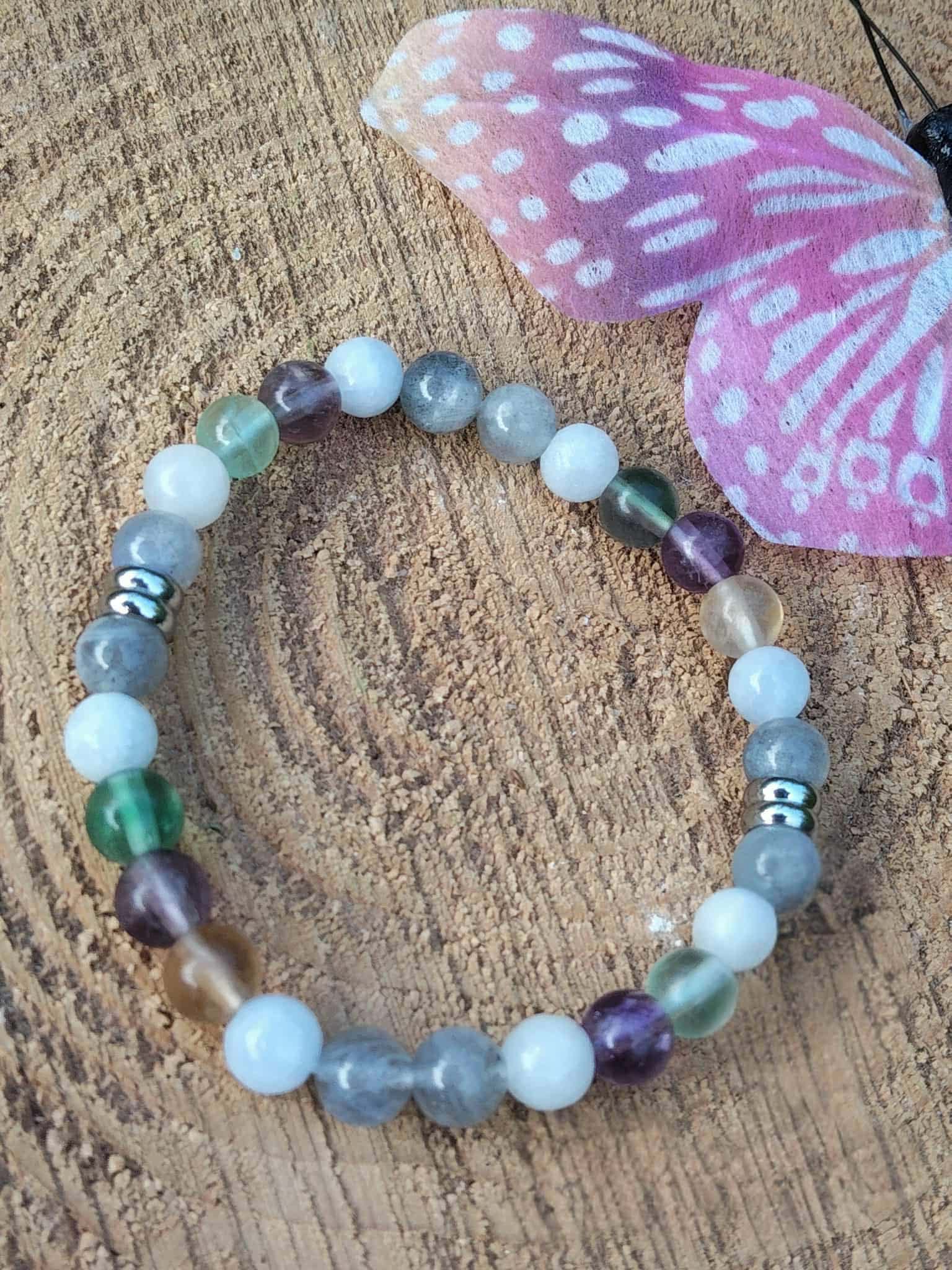 Bijou Énergie lunaire en pierres naturelles sur tranche de bois, décor végétal et champignon violet, création zen pour clarté mentale.