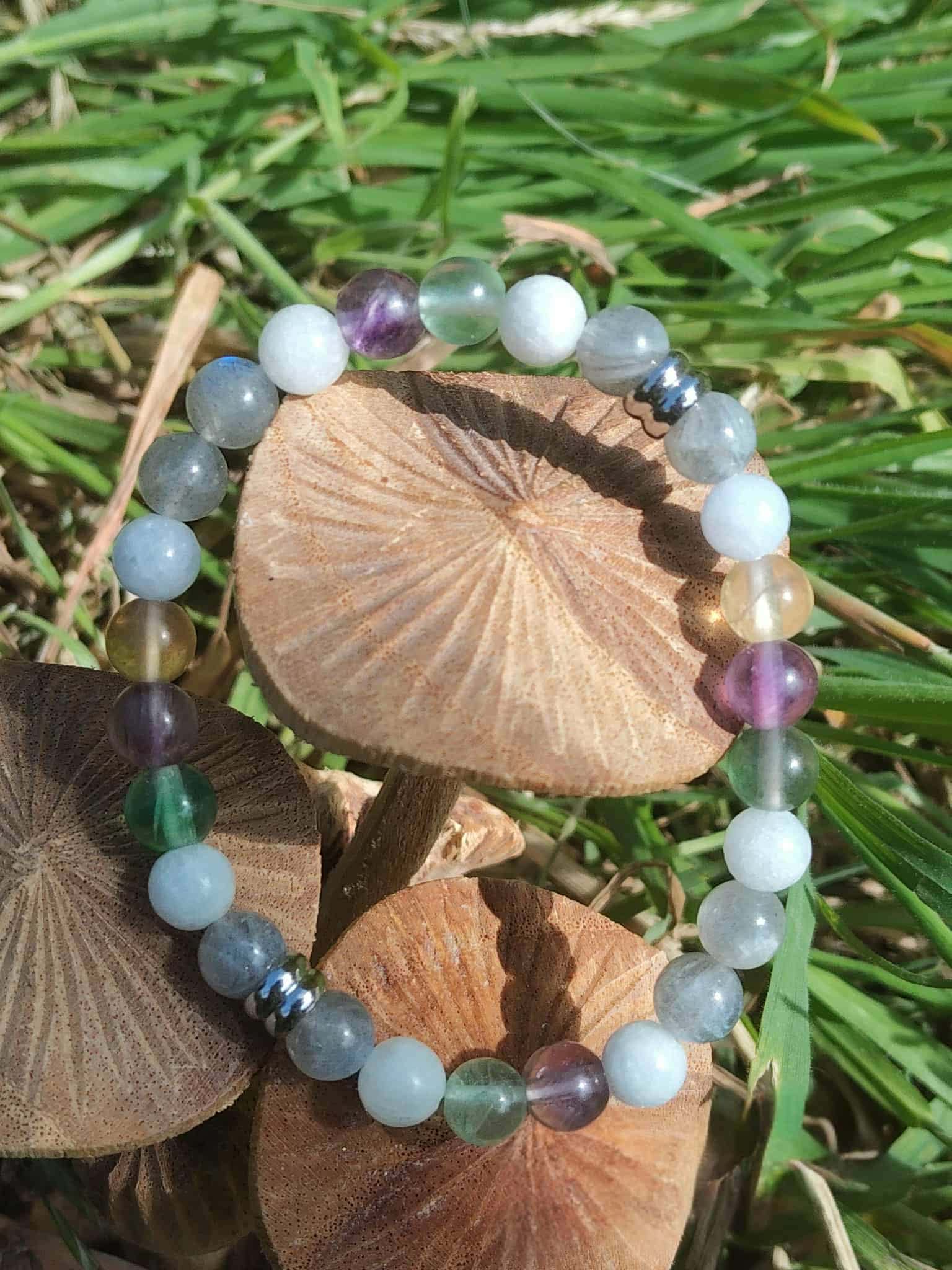Bracelet Énergie lunaire sur herbe verte avec champignons bruns, nuances bleu-gris, vert et violet, équilibre émotionnel et intuition