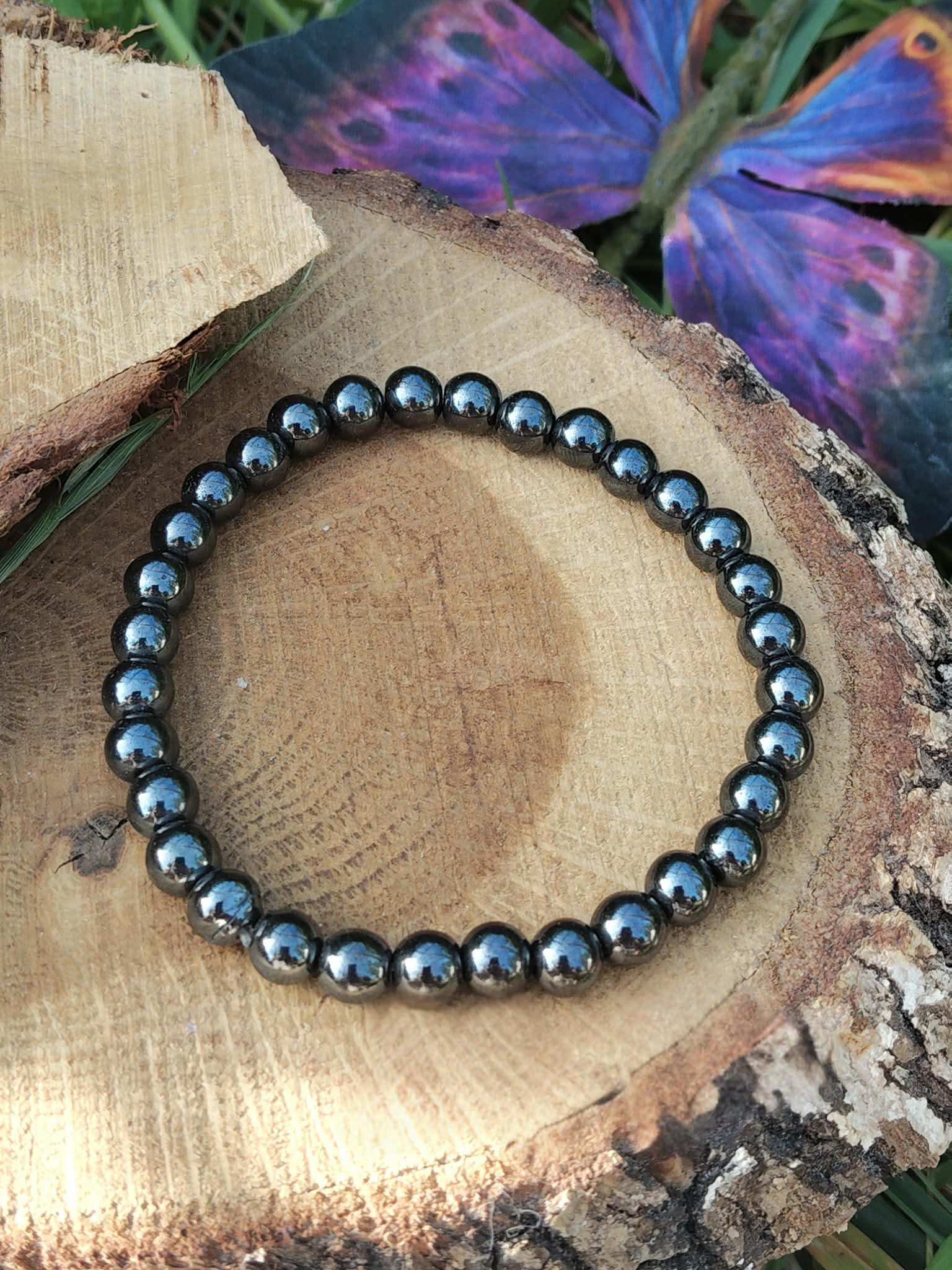 Bracelet hématite 6 mm sur rondin de bois avec aile violette, perles gris métallisé aux reflets bleutés pour discernement, tenue émotionnelle et axe intérieur