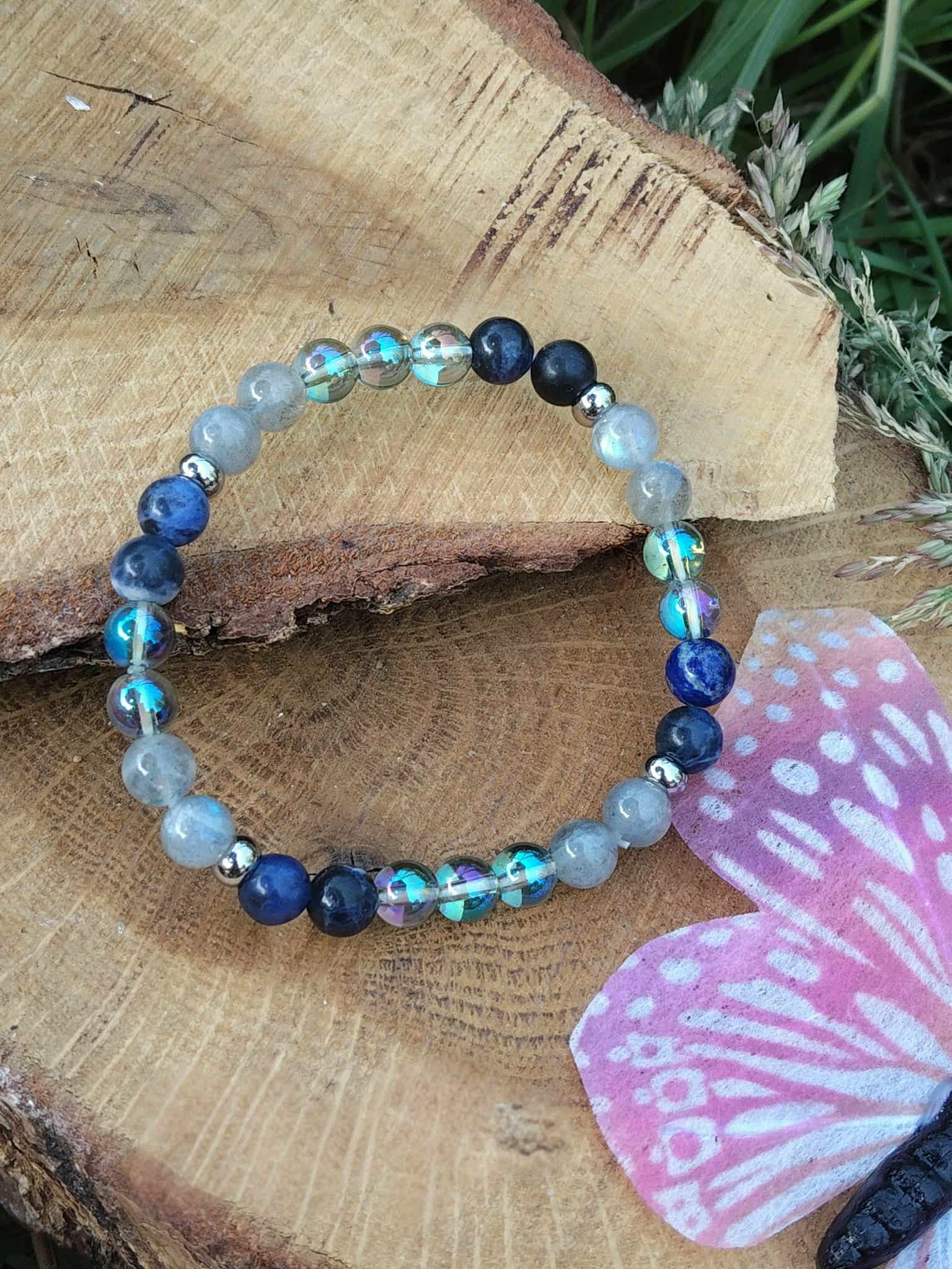 Bracelet Intuition sur rondin de bois brut près d’un champignon rose, labradorite et aqua aura pour apaiser la surcharge mentale et affiner le ressenti