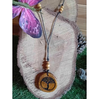 Pendentif Arbre de Vie en bois rond gravé sur cordon noir avec perles bois, posé sur tranche de bois et fleur violette, création nature au symbole d’enracinement
