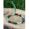 Bracelet prémenstruel 6 mm (malachite, cornaline, cristal de roche) posé sur pierre beige en extérieur, feuillage vert en arrière-plan, création Magic Gaïa; intention apaisement, équilibre émotionnel.