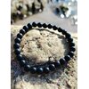 Bracelet shungite 6 mm noir profond sur pierre texturée, photo Bretagne, ancrage solide, protection discrète et esprit plus stable