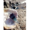 Pendule en fluorite présenté comme outil de divination sur un décor minéral, dans une ambiance douce et mystique évoquant clarté mentale, intuition et recentrage.