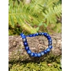 Bracelet Lapis Lazuli 6 mm présenté sur branche en sous-bois avec mousse et fougères, perles bleu profond veinées, intuition et parole apaisée.