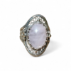 Bague en quartz rose cabochon montée sur argent 925 au design travaillé, posée sur fond clair minimaliste, lumière douce révélant ses reflets laiteux, évoquant apaisement, amour de soi et équilibre émotionnel.