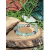 Bracelet fluorite verte et violette en pierres naturelles (8 mm)posé sur rondin de bois en extérieur, bijou de lithothérapie Magic Gaïa pour équilibre émotionnel et clarté mentale.
