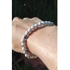 Bracelet howlite blanche 6 mm porté au poignet sur fond sombre, perles blanches veinées de gris pour calme du cœur, retenue émotionnelle et sérénité