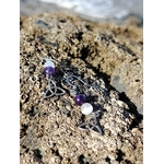 Boucles d’oreilles elfiques triquetra améthyste et sélénite posées sur rocher au bord de mer en Bretagne, création Magic Gaïa, pour apaiser et éclaircir l’esprit.