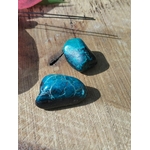 Deux galets de chrysocolle bleu-vert posés sur bois clair en photo minimaliste, pierres roulées évoquant la lucidité, la stabilité émotionnelle et une communication sereine.
