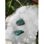 Chrysocolle pierre roulée, deux galets bleu-vert posés sur amas de quartz blanc avec feuillage en arrière-plan, contraste lumineux, pour apaisement, clarté et communication.