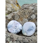 Galet de calcédoine dendritique posé sur un rocher face à la mer en Bretagne, tons bleu-gris marbrés, pierre naturelle associée à la sérénité, à la stabilité et à la douceur intérieure.