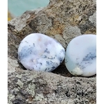 Deux galets de calcédoine dendritique posés sur un rocher face à la mer en Bretagne, teintes bleu-gris marbrées, pierres naturelles associées au recentrage, à la paix intérieure et à la finesse d’esprit.
