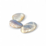 Trois galets de pierre de lune irisés sur fond blanc, reflets bleutés visibles, pierres naturelles reliées à la délicatesse, à la finesse intuitive et à l’harmonie intérieure.