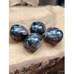 Quatre pierres roulées de grenat almandin rouge sombre posées sur une tranche de bois, pierres naturelles associées au courage, à la persévérance et à l’équilibre intérieur.