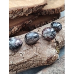 Pierres roulées de grenat almandin rouge sombre posées sur bois naturel, reflets profonds et texture polie, pierres naturelles évoquant la confiance calme, la présence à soi et l’énergie stable.