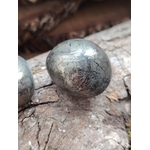 Pierre roulée de pyrite aux reflets métalliques dorés posée sur du bois craquelé, éclat lumineux naturel, pour inviter à la protection, la confiance et la clarté mentale