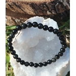 Bracelet obsidienne œil céleste 6 mm posé sur un amas de quartz blanc avec touches végétales, lucidité, recentrage et apaisement profond