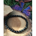 Bracelet obsidienne œil céleste 6 mm sur rondin de bois avec papillon bleu et brins d’herbe, perles noires irisées, introspection, recentrage et discernement."