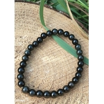 Bracelet obsidienne œil céleste 6 mm en perles noires sur rondin de bois avec brin d’herbe vert, assurance, présence et alignement personnel