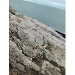 Collier doré à perles facettées vert africain posé sur rocher face à la mer en Bretagne, bijou fin au rendu frais et harmonieux