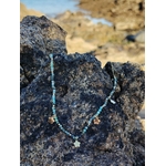 Collier doré vert africain facetté posé sur rocher en bord de mer en Bretagne, bijou féminin aux accents frais et équilibrés