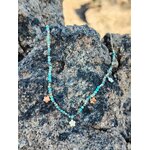 Collier acier inoxydable doré avec perles vert africain et pendentifs fleur photographié sur rochers bretons, élégance légère et esprit nature