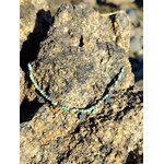 Collier doré en acier inoxydable avec perles vert africain facettées et pendentifs fleur, posé sur rocher marin pour une touche chic et printanière