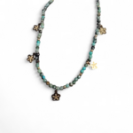 Collier doré vert africain facetté sur fond blanc, pendentifs fleur et acier inoxydable pour une allure lumineuse et délicate
