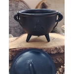 Petit chaudron en fonte noire avec trois pieds sur planche en bois, couvercle au premier plan, accessoire spirituel pour autel.