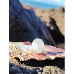 Bague réglable en argent 925 sertie d’une péristérite ovale (pierre de lune arc-en-ciel) posée sur coquillage et rochers en bord de mer, reflets laiteux, intention douceur et intuition.