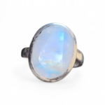 Bague réglable en argent 925 sertie d’une péristérite ovale (pierre de lune arc-en-ciel) sur fond blanc, reflets bleutés, intention douceur, apaisement et intuition.